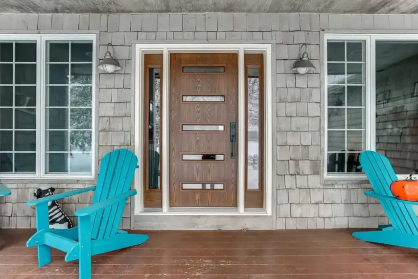 Modern wood grain front door with horizontal glass panels and white trim on a cedar shingle home.